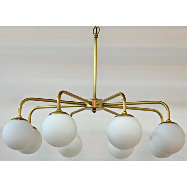 Mid-century modern lines in antique brass finished metal suspend eight glowing orbs in this retro-futurist take on a...