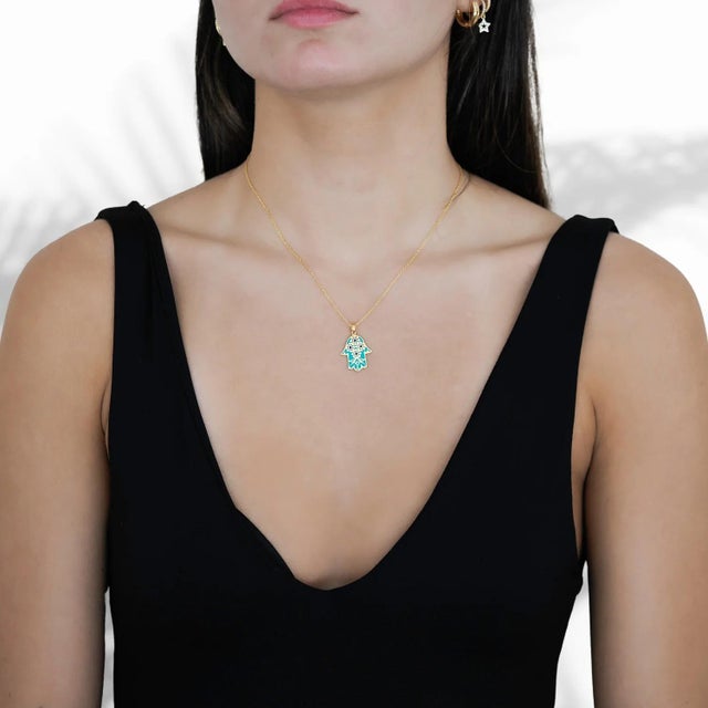 The Floral Hamsa Hand Pendant Turquoise & Gold Necklace a captivating piece of jewelry that combines intricate design,...
