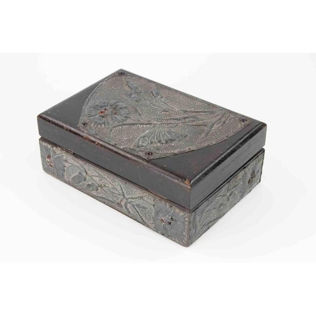 A rectangular wooden casket with hinged lid, adorned with repoussé pewter panels worked in low relief. The decoration...