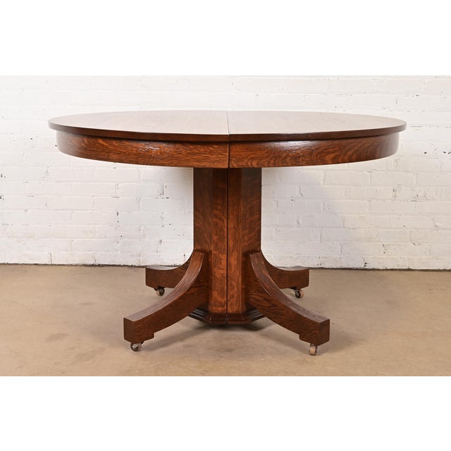 A gorgeous antique Mission, Arts & Crafts, or Late Victorian quarter sawn oak split pedestal extension dining table In the...