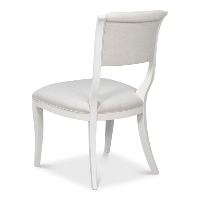 Saber legs sweep outward at both front and back, establishing the recognizable stance of ancient Greek seating. The frame...