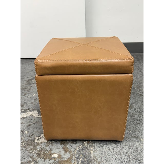 Design Plus Gallery presents the Briggs Storage Ottoman by Grandin Road. This square ottoman has a caramel-toned faux...
