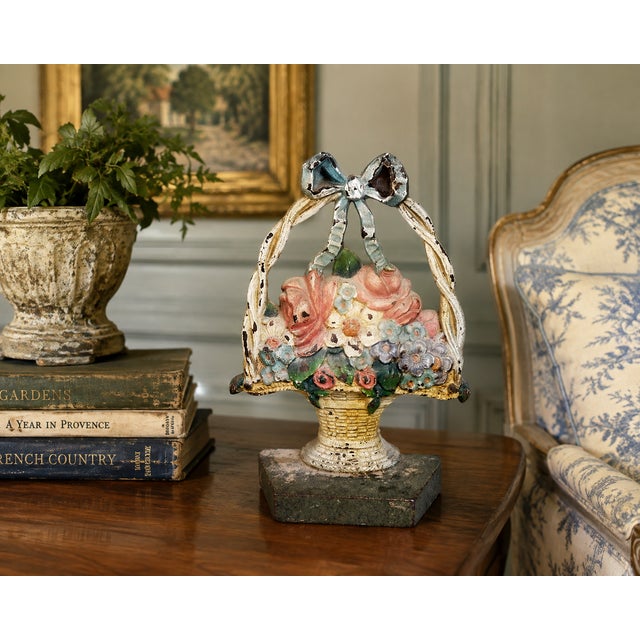 Charming vintage cast iron doorstop modeled as an overflowing basket of flowers beneath an arched handle tied with a bow....