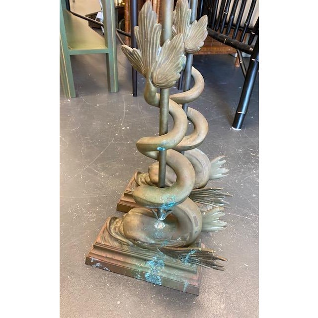 A pair of fine and large cast bronze figural doorstops in the form of a dolphin or serpent with tail wrapped around a...