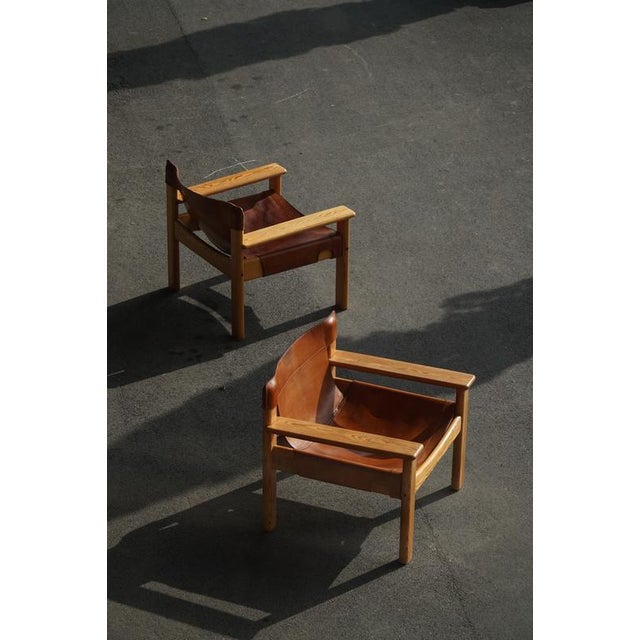 A pair of charming Swedish Mid Century Modern lounge chairs in solid pine, upholstered in leather with a fine patina....
