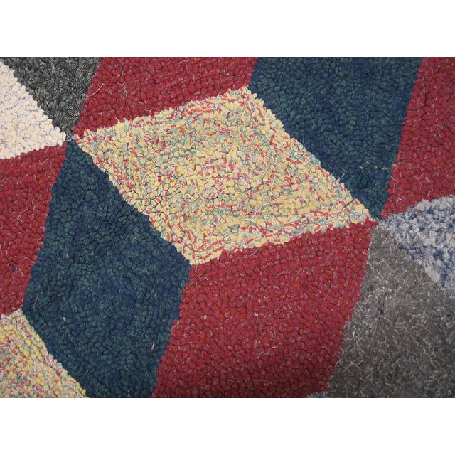 The “tumbling block” design of simultaneously projecting and receding cubes made up of lozenges in red, royal blue, ecru,...