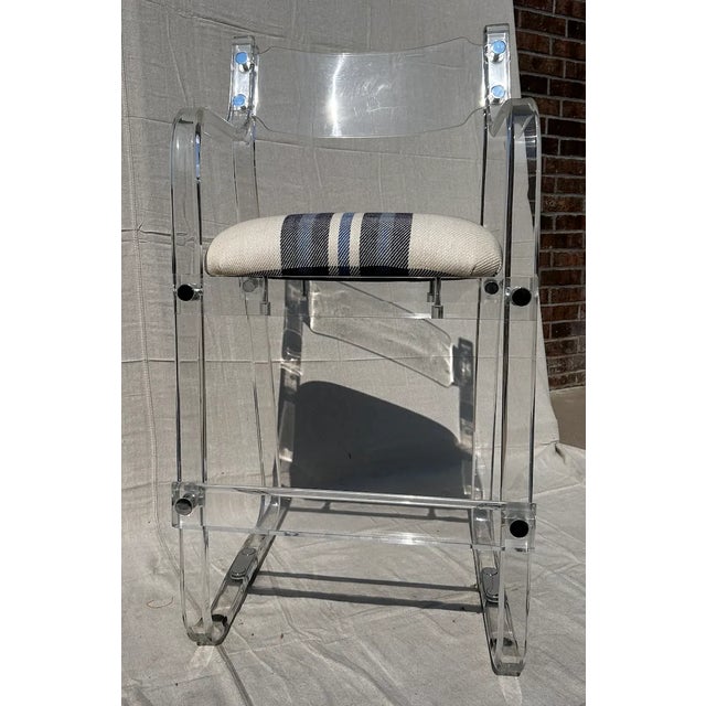 A pair of 1970's counter height lucite barstools with arms and chrome details with upholstered seats