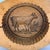 A beautifully carved antique Swiss wooden butter mold featuring a pastoral cow motif framed within a scalloped oval...