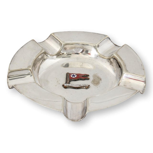 English silverplate ashtray by Mappin & Webb featuring the enamel flag badge of the S.S. Arandora Star. Originally...