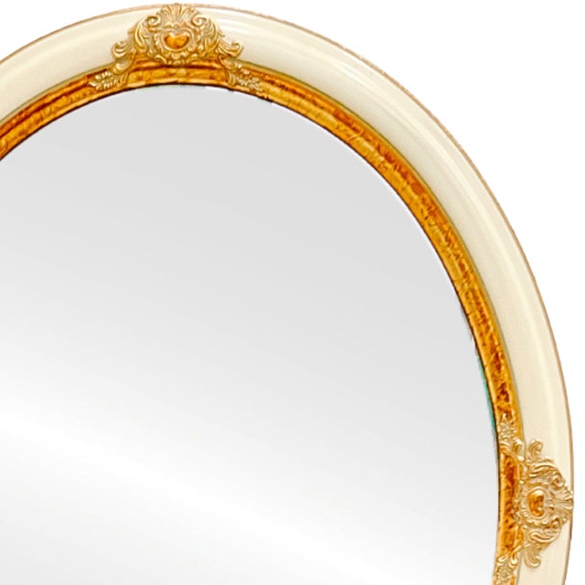A beautiful 1980s vintage French Provincial style oval wall mirror in a cream and gold finish. Made of sturdy wood...