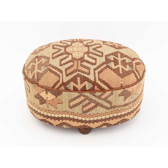Oval Kilim Upholstered Footstool, mounted on four ball form wood feet. 11" H x 18.5" W x 14.25" D. Provenance: A Sutton...