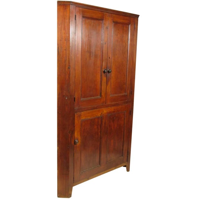 An early 19th-C. American pine corner cabinet. Features an upper compartment fitted with a fixed shelf secured by a pair...