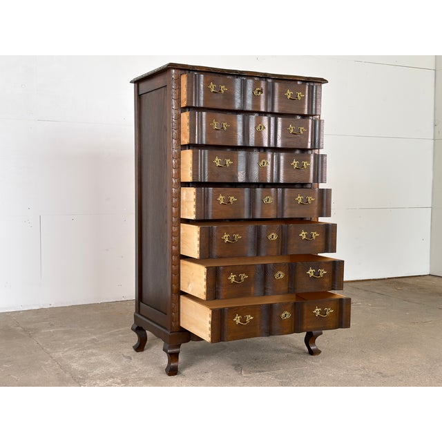 A dark-stained solid oak serpentine tallboy chest of drawers in the Danish Baroque Revival tradition — the work of an...