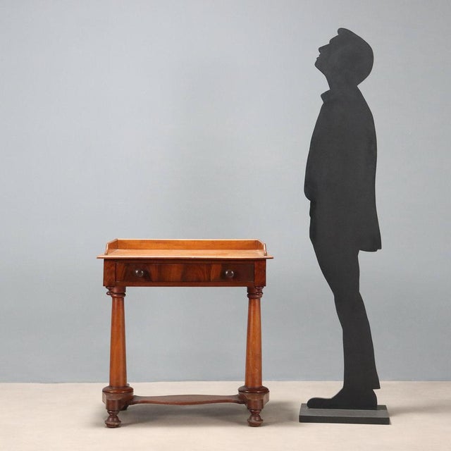 Small mahogany writing desk. Drawer in the lower section, upper balustrade, two turned legs resting on a molded base...