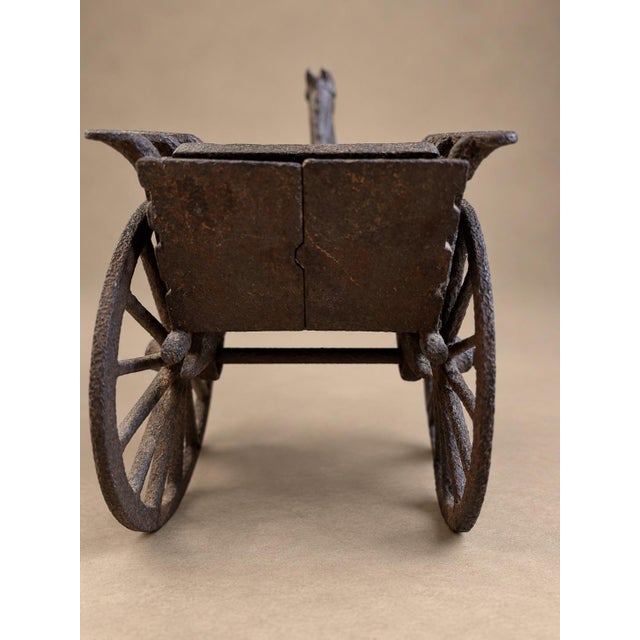 Antique cast iron horse and sulky cart featuring a sculpted horse, large spoked wheels, and a textured carriage seat. Its...
