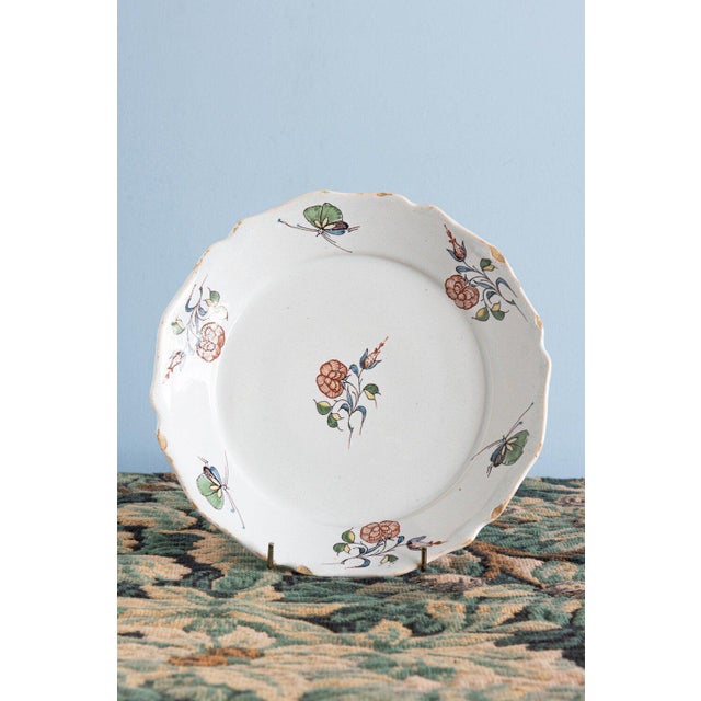 This pair of 18th-century French faience plates from La Rochelle is decorated with an elegant spray of red flowers, blue...