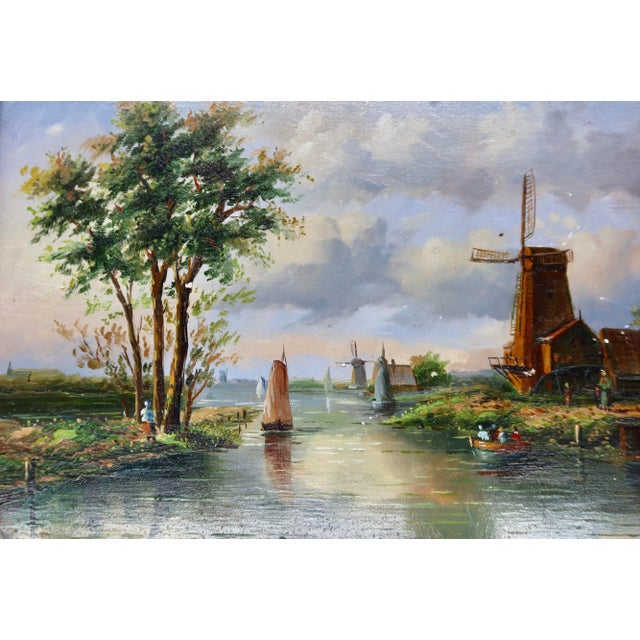 A luminous and tranquil riverside landscape depicting a working windmill, sailing vessels, and figures along a tree-lined...
