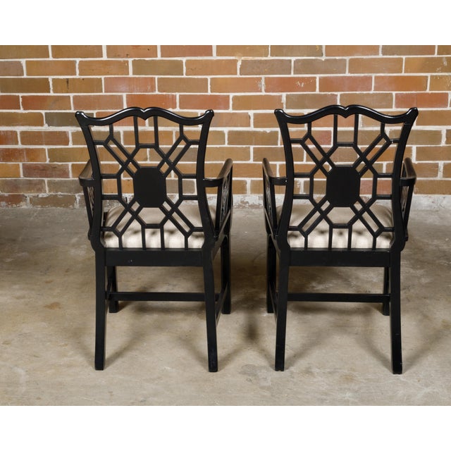 A pair of English Chinese Chippendale style black lacquered armchairs from circa 1950 with upholstered seats. This elegant...