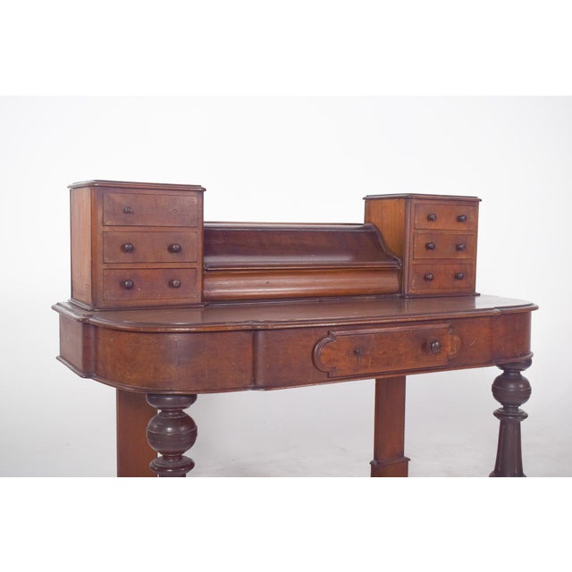 Desk with turned feet. The top has an overlap of small side compartments made up of symmetrical drawers, six in all, as...