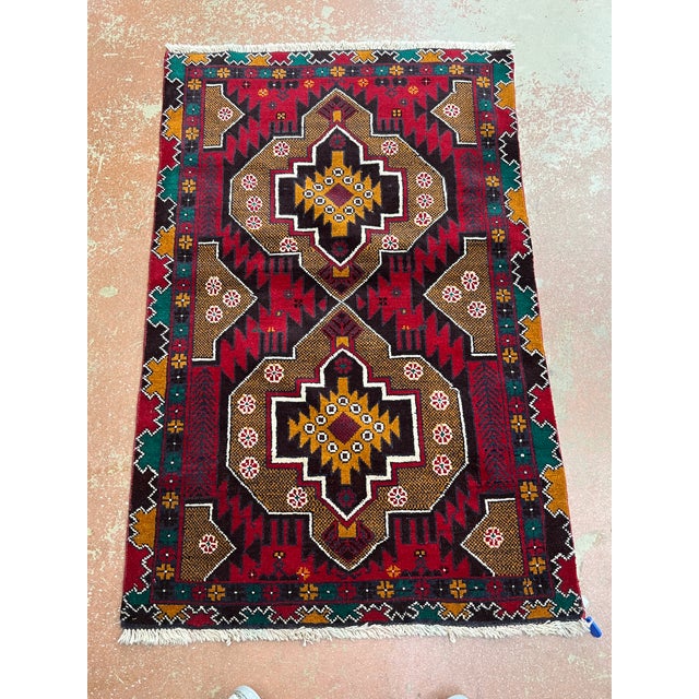 Afghan Balouch rug, hand knotted in Afghanistan from 100% wool. Measuring 2’11” x 4’7”, this vibrant tribal rug features...