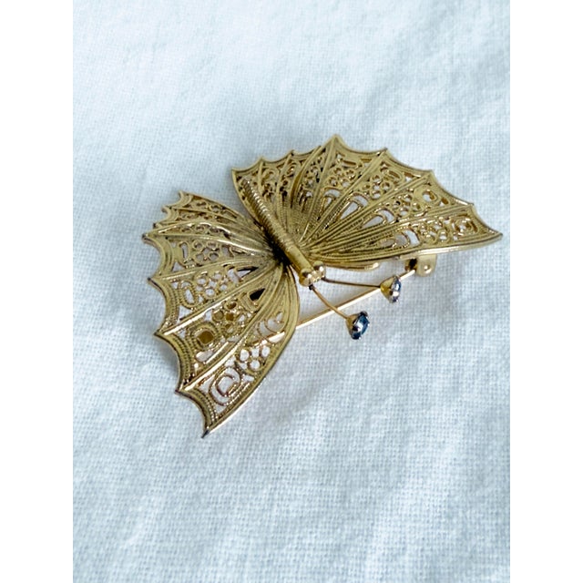 Vintage 1960s gold-tone filigree butterfly brooch in an Art Nouveau Revival style with openwork lace-style wing...