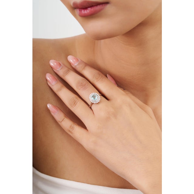 This elegant double halo cocktail ring features a 1.18-carat oval-cut natural Paraíba tourmaline, set in 14k yellow gold....