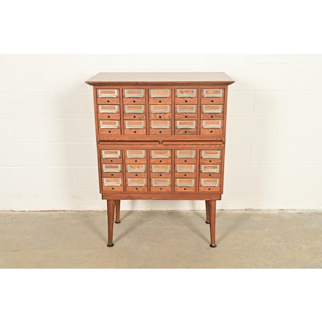 A beautiful Mid-Century Modern 30-drawer library card catalog or file cabinet with two pull-out writing tablets In the...