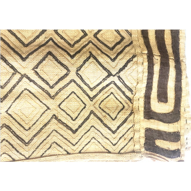 A rectangular hand woven raffia textile featuring intricate geometric embroidery and appliqué designs. Originating from...