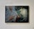 The artwork depicts a serene figure draped in intricate lace, gently releasing a stylized, glowing bird from her hands....
