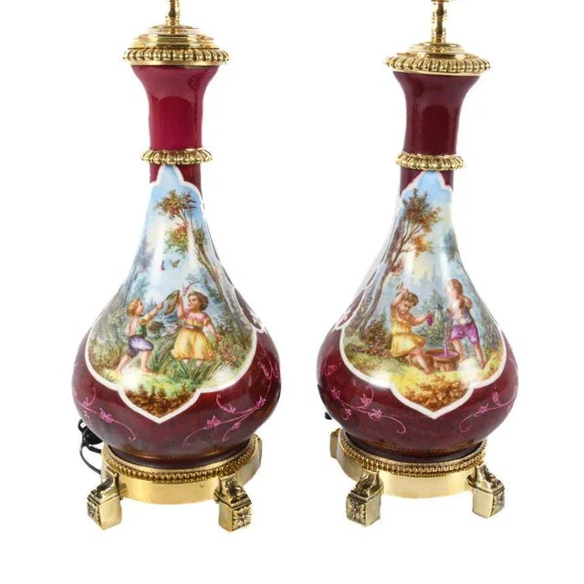 A refined pair of mid-century porcelain table lamps in the French Rococo or Louis XV style, each exquisitely hand-painted...