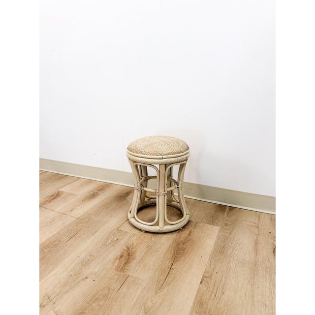 This charming vintage lightwash rattan stool with woven wicker seat is a beautifully crafted coastal and Hollywood Regency...