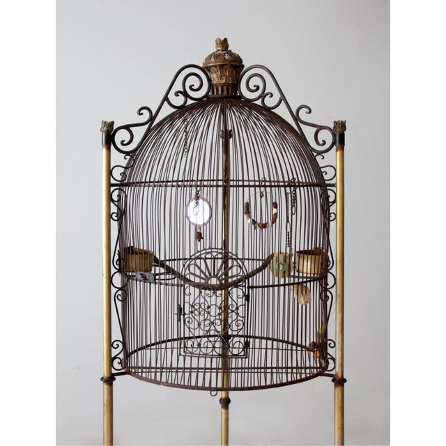 This is a 20th century French Victorian style birdcage. The monumental black iron dome cage features a golden tripod base...