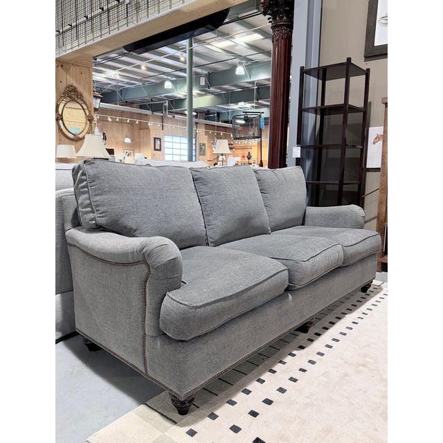A tailored Bassett sofa upholstered in soft grey linen, offering a clean and inviting silhouette with timeless appeal. The...