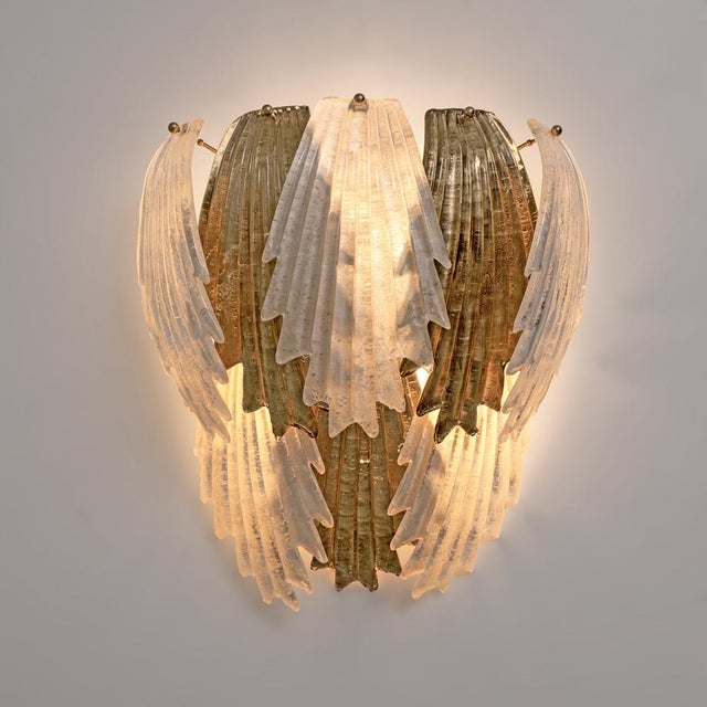 An elegant italian art deco wall sconce, featuring a sculptural composition of murano glass leaves layered in textured...