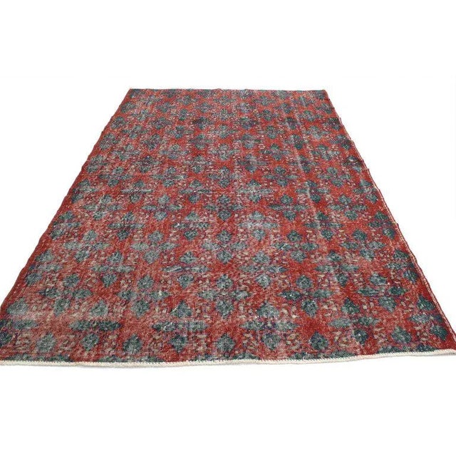 This distressed vintage Turkish Sivas rug features an all-over geometric pattern composed of four-petal leaves and...
