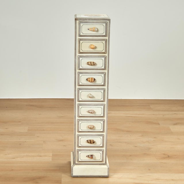 Charming tall, thin nine drawer chest featuring a painted seashell motif on a pale grey background and organic seashells...