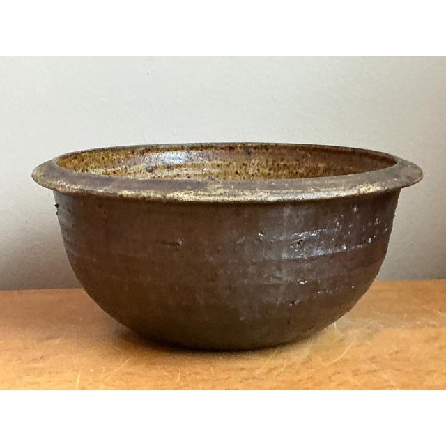 This vintage handcrafted stoneware bowl takes a deep, rounded hemispherical form, rising from a gently tapering base to a...