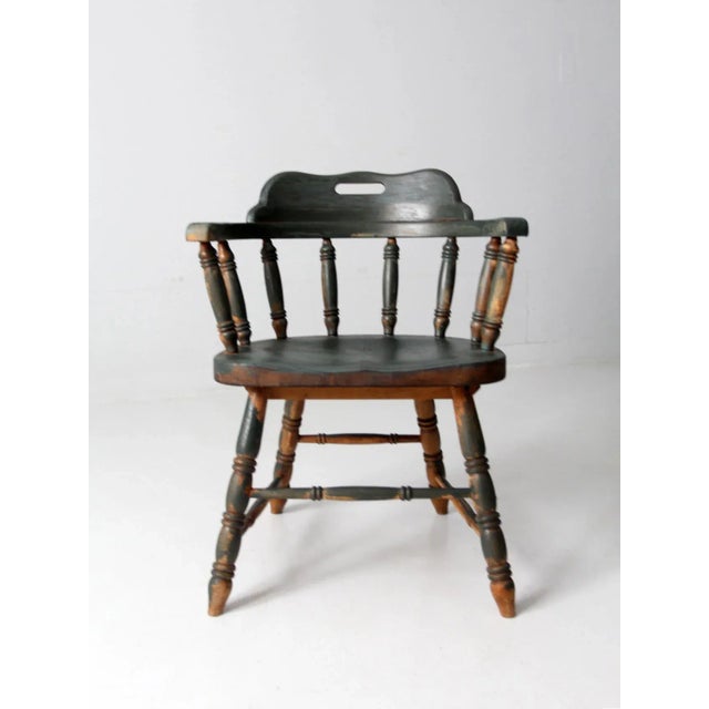 This is a classic early 20th century vintage captains chair. With a dark emerald green paint wash, the heavy oak armchair...