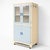 charming vintage kitchenette pantry cabinet, finished in a soft pale yellow with powder blue doors, capturing the cheerful...