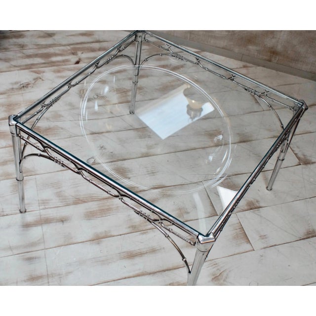 This faux bamboo side table in aluminum and glass dates to the 1950s.