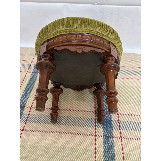 Antique Victorian-style round footstool featuring a floral cushion a ruched olive-green velvet trim, and a hand-carved...