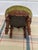 Antique Victorian-style round footstool featuring a floral cushion a ruched olive-green velvet trim, and a hand-carved...