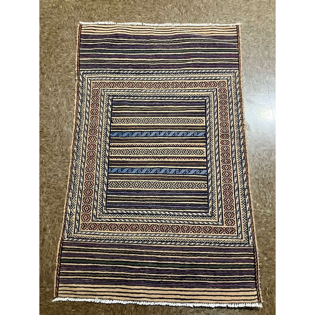 Handwoven Persian kilim flatweave rug featuring a structured composition with a central panel of horizontal stripes...