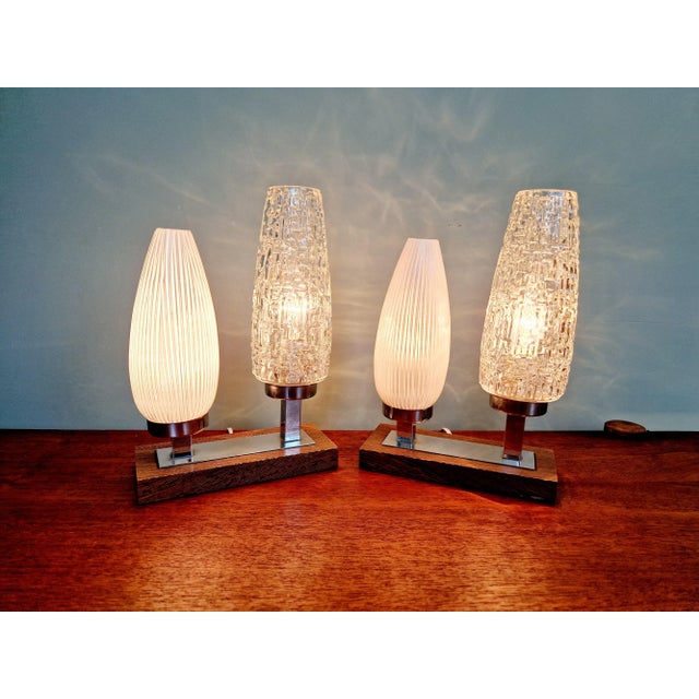 Pair of mid-century bedside lamps with a wooden and chrome-plated metal base and two tubular glass bobeches, 1950s-60s....
