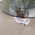This is a unique glass-top coffee table featuring a sculptural seashell base shaped like an open clam Base Material &...