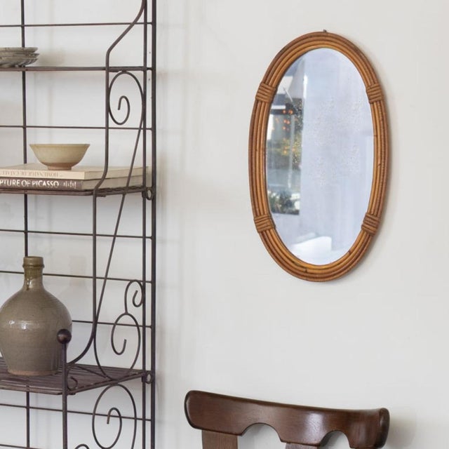 Beautiful vintage rattan mirror from France, 1960s. Oval stacked rattan frame encompassing mirror. Original rattans show...