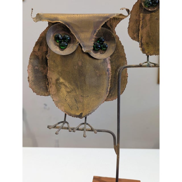 Torch-cut brass owl sculpture with green glass eyes on wood base. Studio Brutalist metalwork.