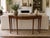 A finely crafted Maitland Smith console table in the English Adam style, distinguished by its serpentine front and richly...