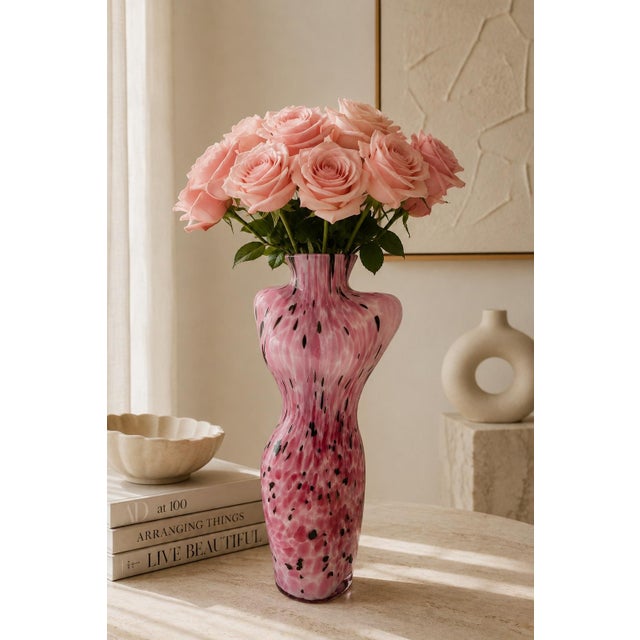 Striking vintage art glass vase sculpted in the form of a female torso, featuring luminous pink glass with white swirled...