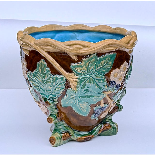 A richly glazed majolica jardinière, featuring deeply modeled leaves, vines, and berries in high relief. The naturalistic...